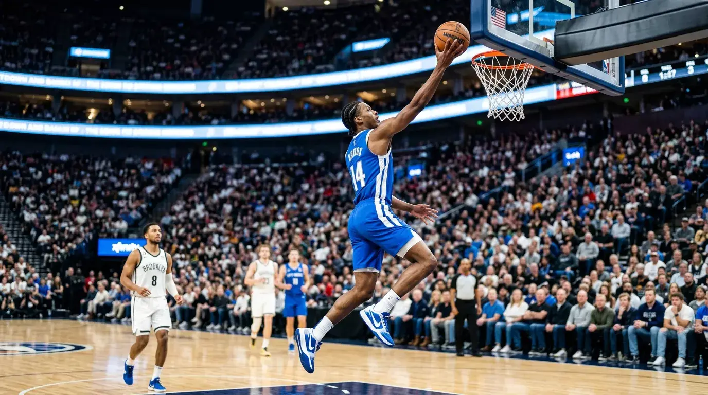 Basketbalspeler die een lay-up maakt in een verlichte sporthal met toeschouwers